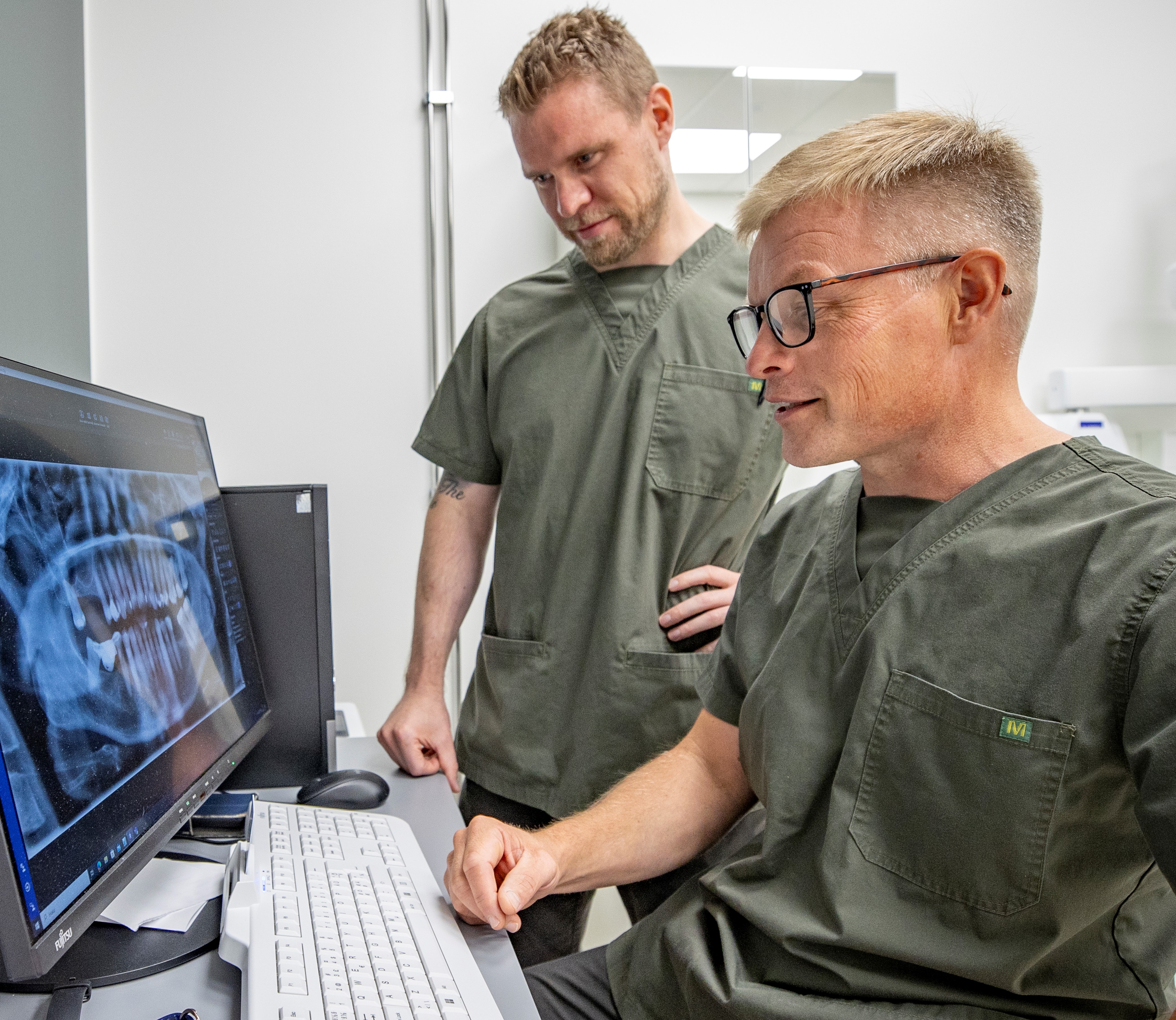 Hammaslääkärit Eero-Matias Saviluoto ja Ismo Raitakari katsovat tietokoneelta hampaiden röntgenkuvaa.